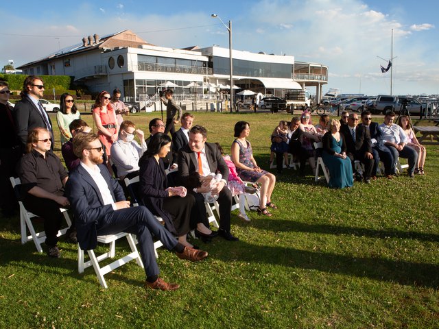 A small group of people watch Rob and Minh's wedding